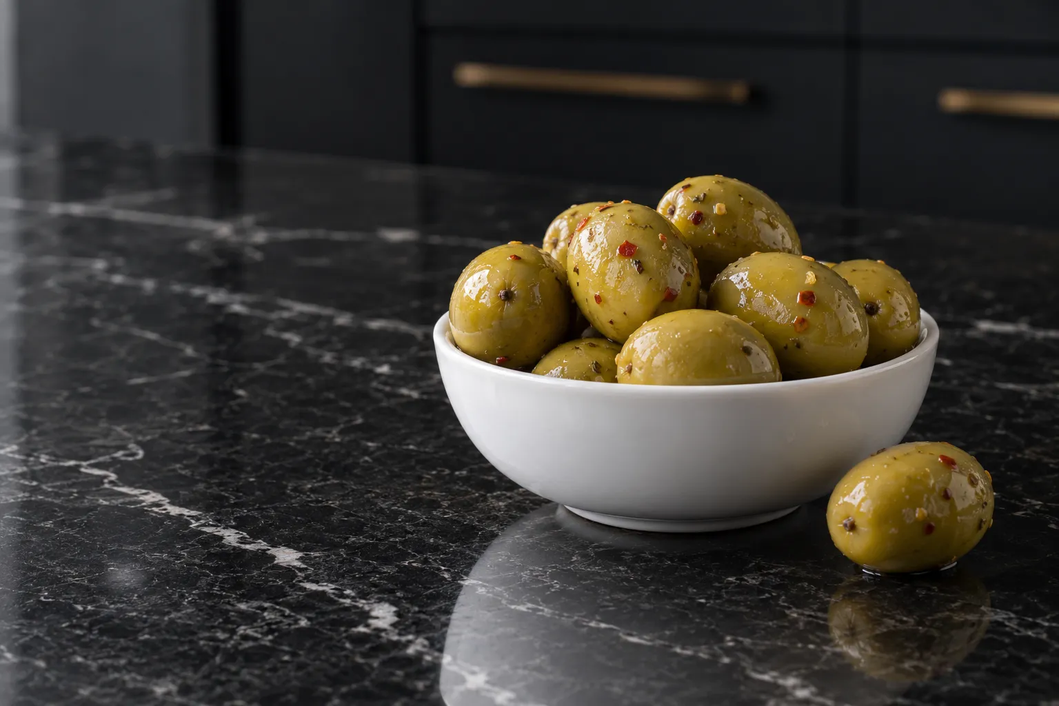 Large green Gordal olives in a white bowl on black marble