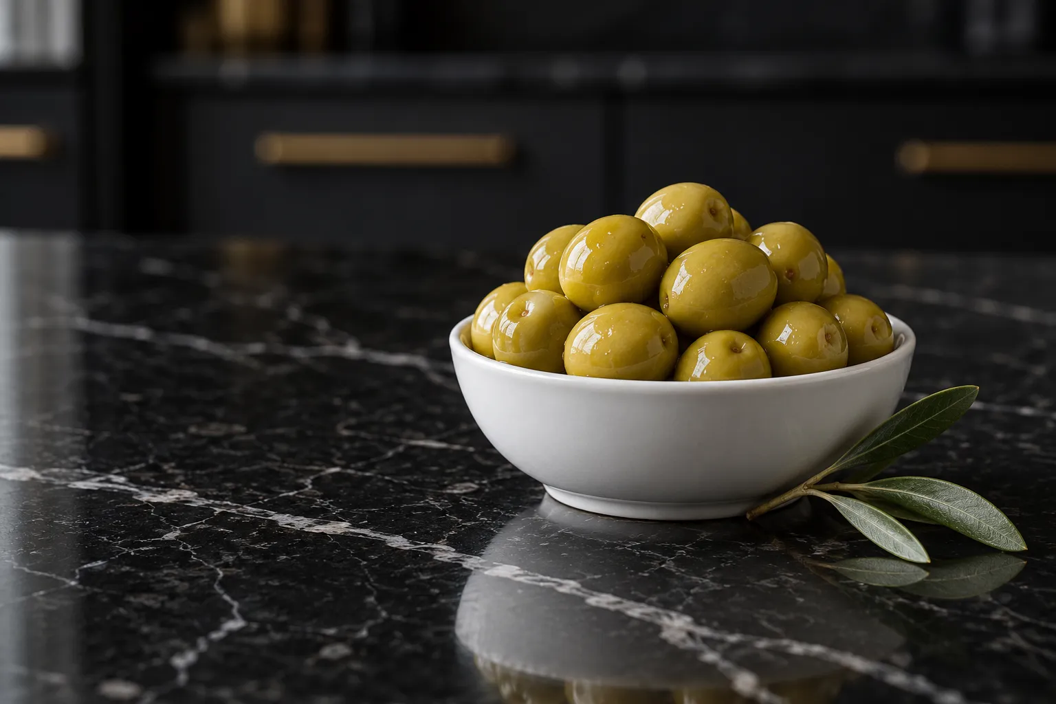 Round green Manzanilla olives in a white bowl on black marble